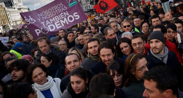 Pablo Iglesias with Juan Carlos Monedero, center right, leader of Spanish Podemos (We Can) left-wing party, smiles as he marches to give a speech at the main square of Madrid during a Podemos (We Can) party march in Madrid, Spain, Saturday, Jan. 31, 2015